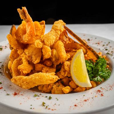 Mixed fried seafood platter, garnished with fresh herbs and lemon wedge.