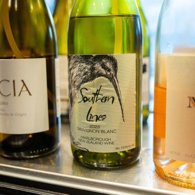 A row of three wine bottles on a shelf in a wine dispenser.