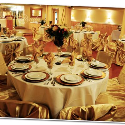 Elegant banquet tables featuring gold chair covers, white linens, and formal settings.