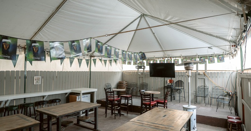 Outdoor patio with canopy, wooden tables, chairs, and a television.