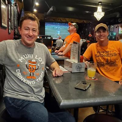 Two guys, one in gray and one in orange shirt posing for a photo