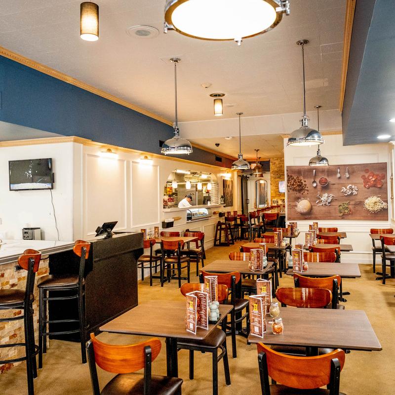 Interior of a cozy restaurant with wooden tables, chairs, pendant lights