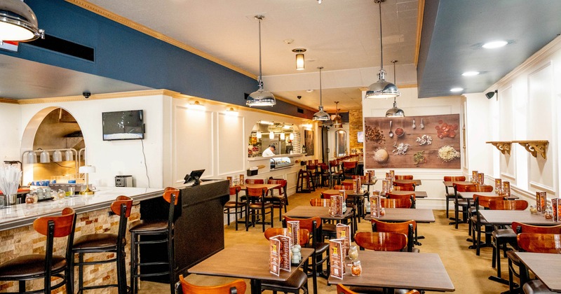 Interior of a cozy restaurant with wooden tables, chairs, pendant lights