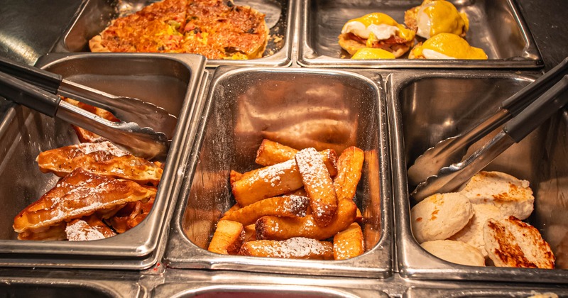 A variety of breakfast foods arranged in a steam table buffet