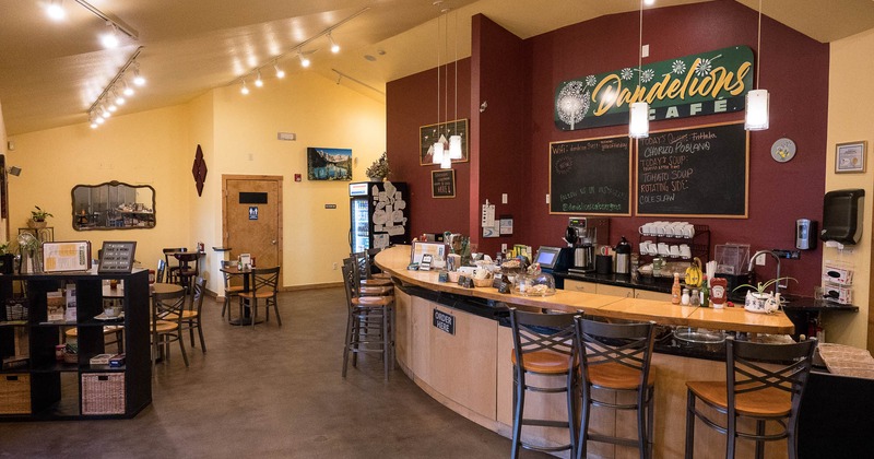 Interior, bar with stools on the right, tables and chairs ready for guests on the left