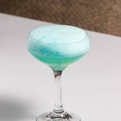 Light blue cocktail drink served in a coupe glass.