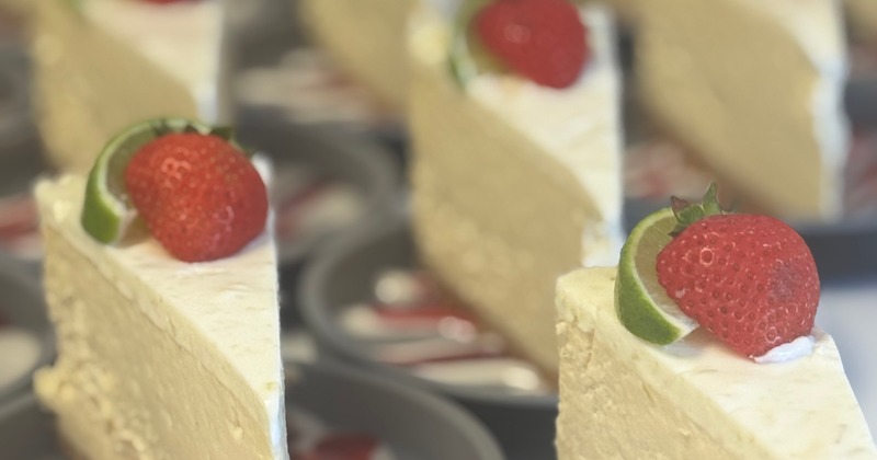 Several slices of cheesecake, garnished with a strawberry and a slice of lime