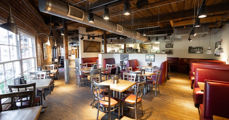 Interior of a rustic restaurant with wooden floors, and red booths