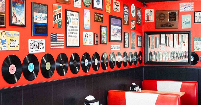 Dining booths, a wall decorated with vintage posters, vehicle registration plates, vinyl records