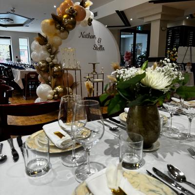 Event table setup with a floral centerpiece and a balloon installation in the background.