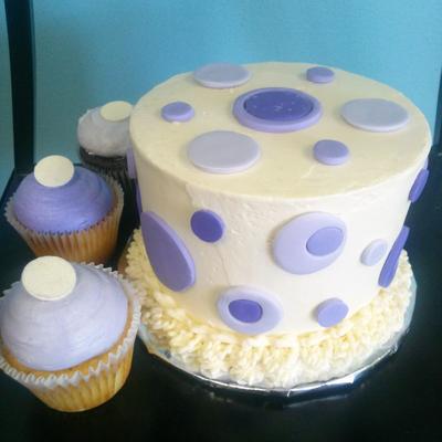 Creamy cake with lavender and purple polka dots, accompanied by matching cupcakes.