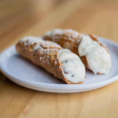 Cannoli filled with a ricotta filling and dusted with powdered sugar.