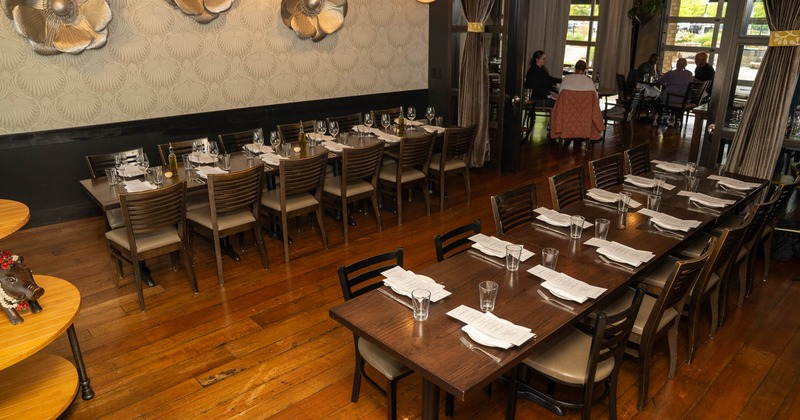 Elegant restaurant interior with two long wooden tables set for dining