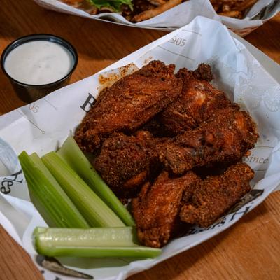 Basket of chicken wings served with celery sticks and ranch dipping sauce.
