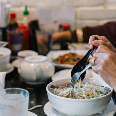 The guest consumes the dish, hands above the plate, diner area behind.