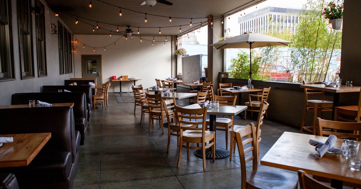 Covered patio with tables, chairs, ceiling fan, and a parasol