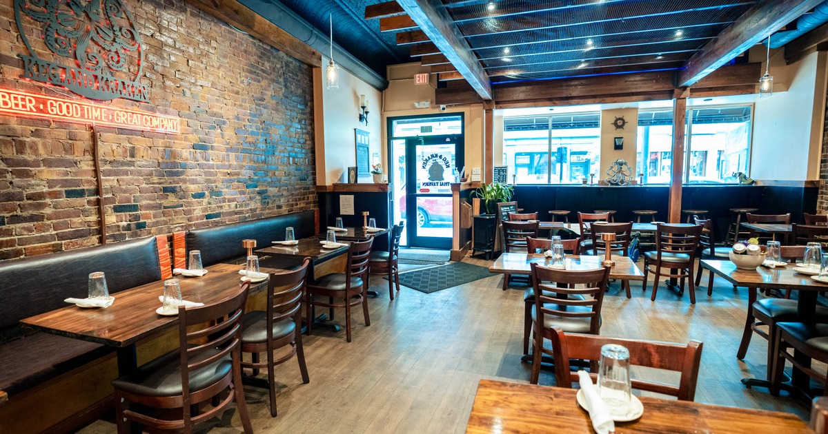 Cozy interior with wooden tables and brick walls, featuring a red neon sign.