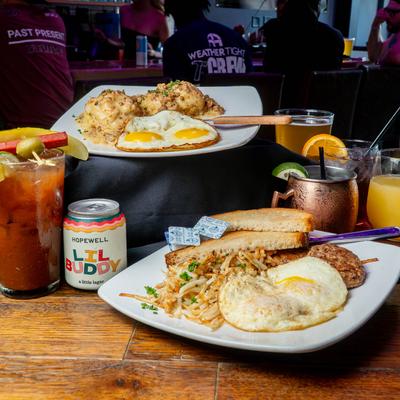 Two breakfast plates and assorted drinks displayed on a table in bar area.