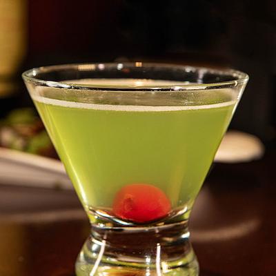 Green Martini garnished with a red cherry.