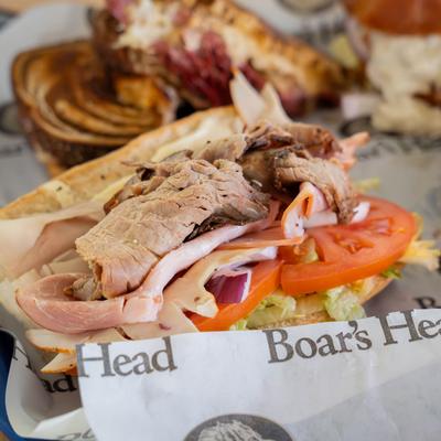 Sandwich with roast beef, ham, turkey, lettuce, tomato, red onion, and mayo.