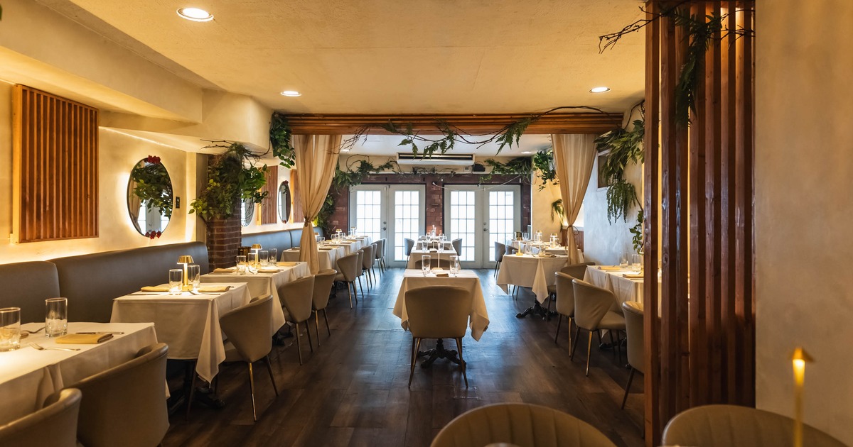 A warmly lit restaurant interior with neatly arranged tables and beige chairs