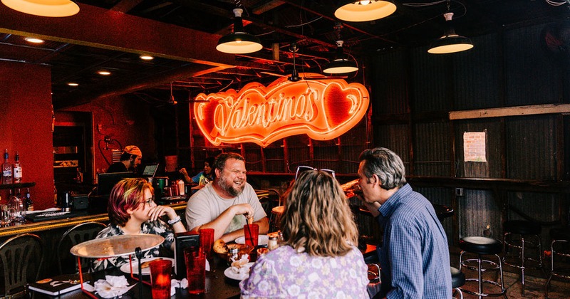 Interior, people dining at a table in seating area near a bar