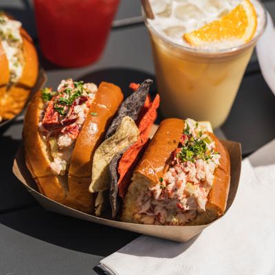 Lobster roll served with tortilla chps, alongside a drink.