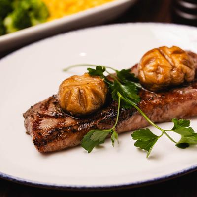 New York Strip served with mushrooms and parsley garnish.