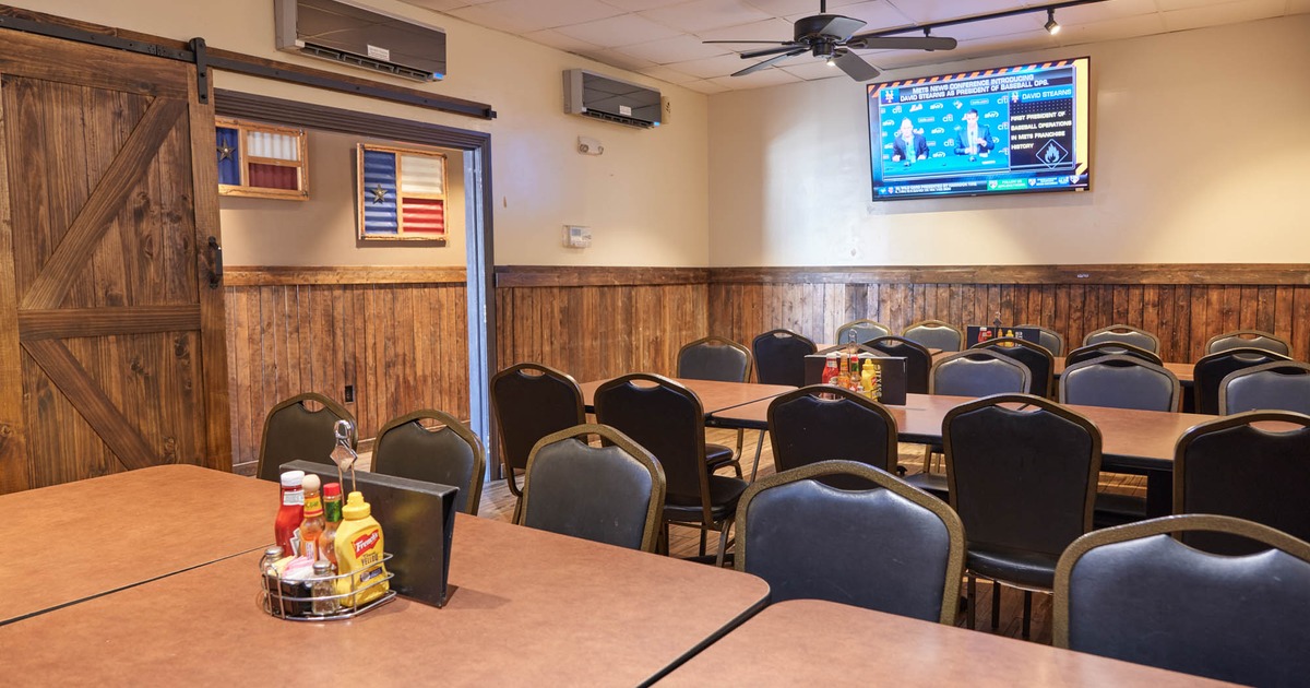Interior featuring tables and chairs arranged in front of a television screen