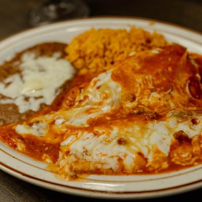 Mexican combination plate featuring cheese enchiladas with red sauce, rice, and refried beans.