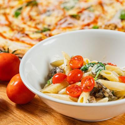 Penne Alfredo pasta, with cherry tomatoes, mushrooms, and basil.