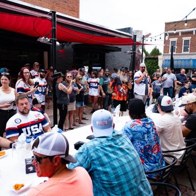 Crowd of people gathered at tables and standing around at the event.