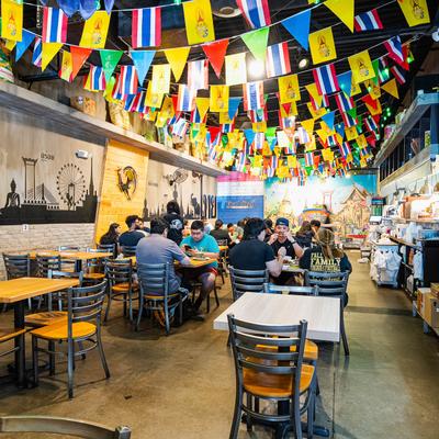Busy Thai restaurant interior with colorful flags and wall murals.