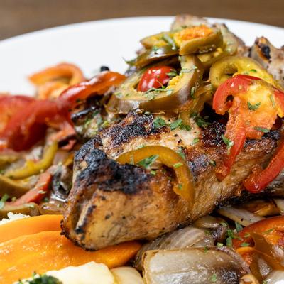Veal chop with peppers, onions, and other vegetables.