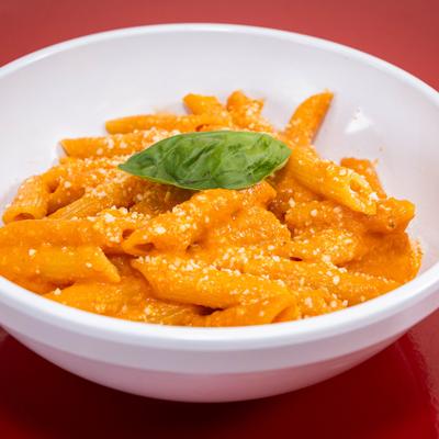 Penne A la Vodka topped with graded cheese and fresh basil.