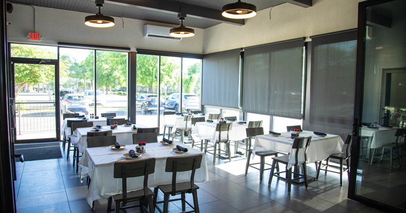 Interior with white tablecloths, large windows, and metal chairs