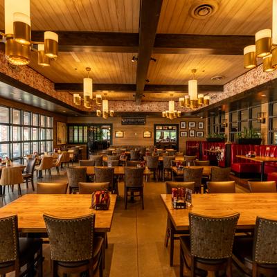 Restaurant interior featuring red booth seating, wooden tables, and pendant lights.