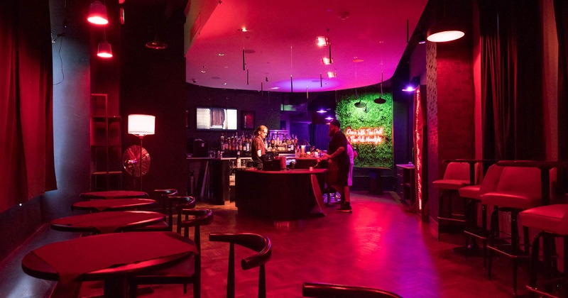 Interior, seating area, tables and chairs, wooden flooring, bar, green wall in the back