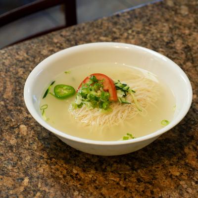 Noodle soup topped with scallions, tomato and jalapeno.