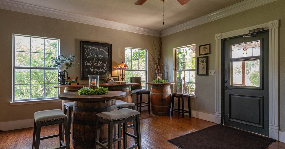 Interior, event space, decorated barrel tables and bar stools, windows, a ceiling fan