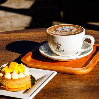 Latte and Mango Tart served on a wooden table.