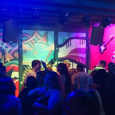 Crowd dancing in the nightclub with colorful stage lights.