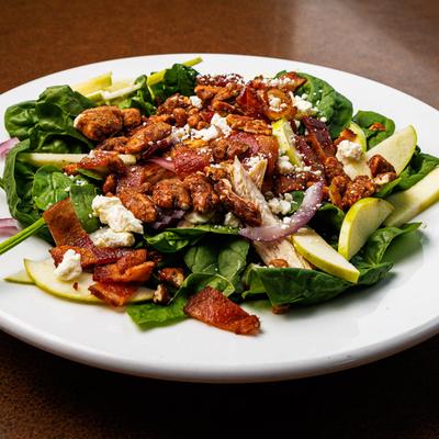 Salad with spinach, pecans, cheese, and apple slices.