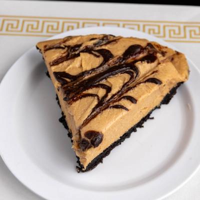 Slice of peanut butter pie with chocolate drizzle on a white plate.