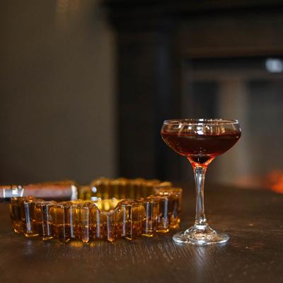 Manhattan cocktail, lit cigar and an ashtray