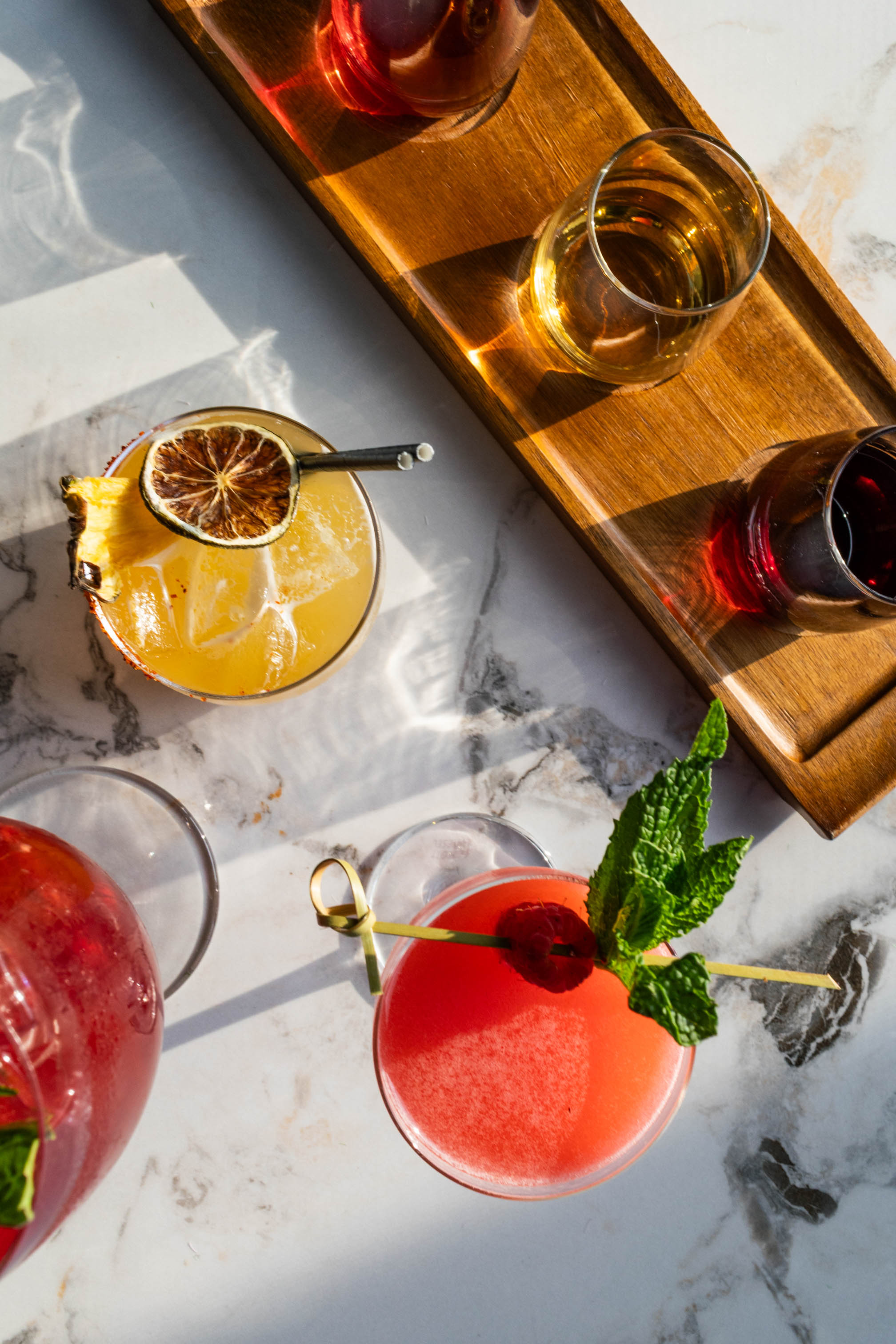 an assortment of colorful wines and cocktails on white marble table