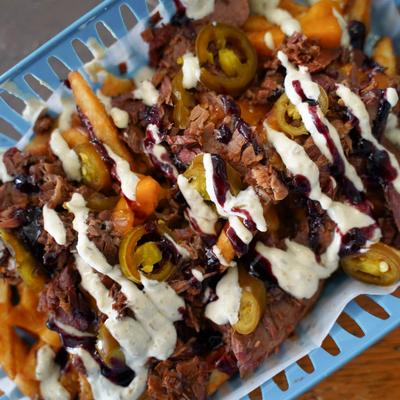 Loaded fries topped with shredded beef and jalapenos, drizzled with sauces.