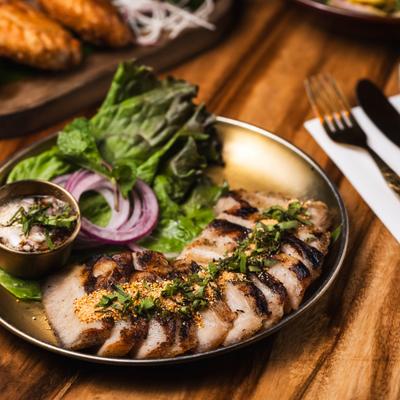 Grilled Pork Jowl served with a fresh salad and a dipping sauce.