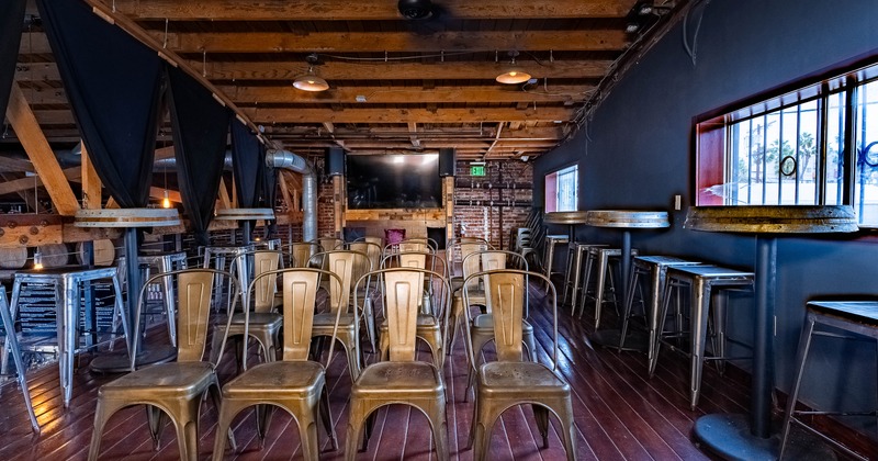 Interior with metal chairs arranged in rows, high tables and chairs and wooden beams on the ceiling