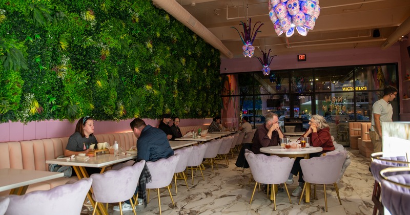 Diner area, tables and chairs, green plants wall, interesting skull chandeliers